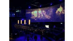 A model of the Titanic lit up with blue and yellow lighting at the Titanic museum in Belfast