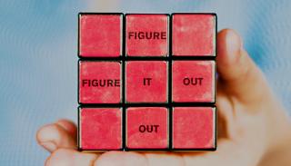 A red rubric cube that says 'figure it out' horizontally and vertically