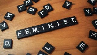 Black letter tiles spelling the word 'feminist'