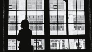 A silhouette of a person looking out a window