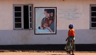 Image of African woman walking past a mural.