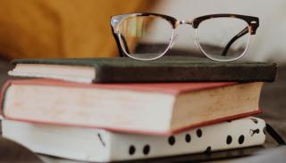 An image of a pair of glasses atop a pile of books