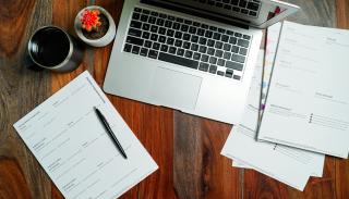 A laptop, plant, and stack of papers