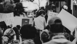 A young girl lifted up at a protest in black and white
