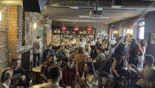A photo of the PGN and first timers meet up at #BISA2025 in The Sunflower Pub. There is a large crowd of people talking.
