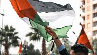 Man at a Palestine protest waving a Palestinian flag