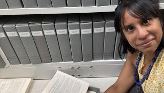 Picture of a women with short brown hair reading papers on the floor