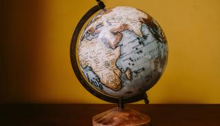 A wooden globe against a mustard background.