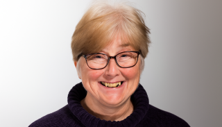 A headshot of Kimberly Hitchings wearing a navy polo neck jumper