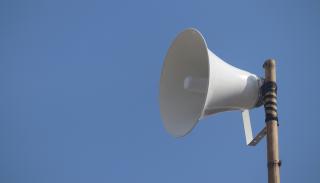white megaphone on a pole with the blue sky as a background