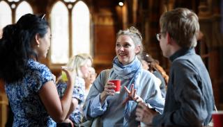 3 BISA conference attendees having a conversation around a table holding a cup of tea