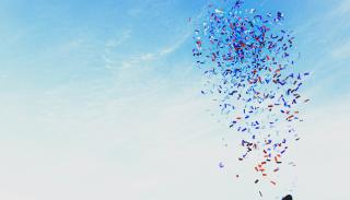 a person shooting a confetti cannon into the blue sky
