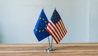 A European and US flag ontop of a wooden table 