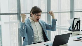 A man in a suit jacket throwing up his arms in excitement