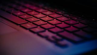 Softly blurred close up image of a laptop keyboard and the glow of a half closed laptop screen 