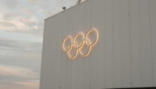 Glowing olympic rings against a white building 
