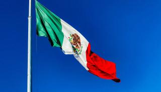 Mexican flag flying over a deep blue sky