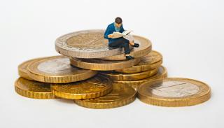 figurine man sat on top of a stack of coins