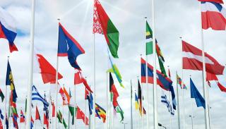 Multiple nations flags on poles in the sky