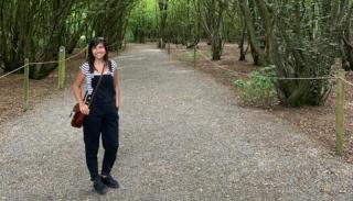 Holly Ryan stood in woodland wearing dungarees