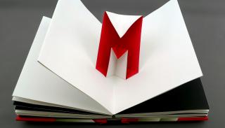 An open book with a pop up 'M' in red