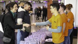 A BISA 2026 conference volunteer giving a name badge to a delegate