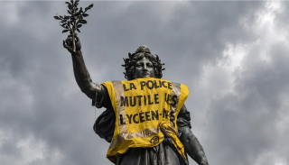Action organised by Extinction Rebellion. Statue of Marianne at Place de la République, Paris, draped in a high-visibility yellow vest featuring the protest slogan: “La police meutile les lycéen·nes” (The police mutilate high school students)