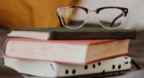 A pair of glasses on top of a stack of books