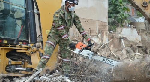 Man in camo cutting wood with a chainsaw
