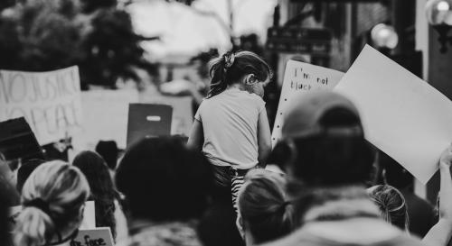 A young girl lifted up at a protest in black and white