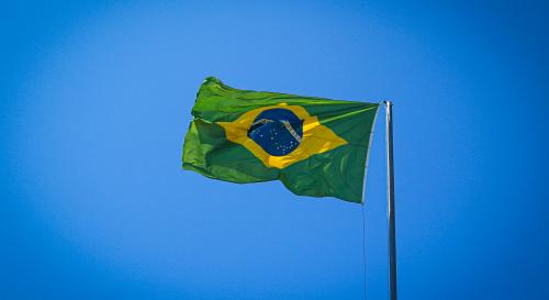 A Brazilian flag flying against a blue sky 
