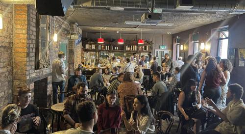 A photo of the PGN and first timers meet up at #BISA2025 in The Sunflower Pub. There is a large crowd of people talking.