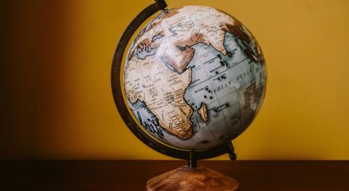A wooden globe against a mustard background.