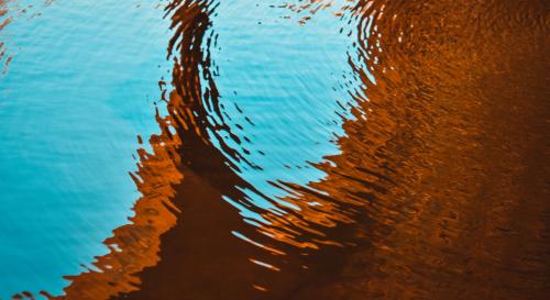 A pool of water reflecting a brown and orange shadow