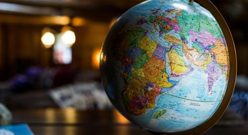 Multicoloured globe on a desk back lit by golden lighting.