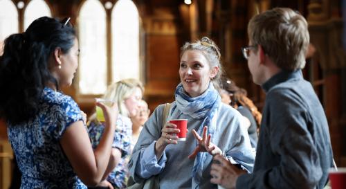 3 BISA conference attendees having a conversation around a table holding a cup of tea