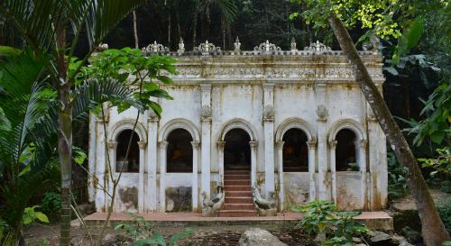 A UNSECO heritage site of an old white building with 5 large windows situated in a forest with greenery surrounding it