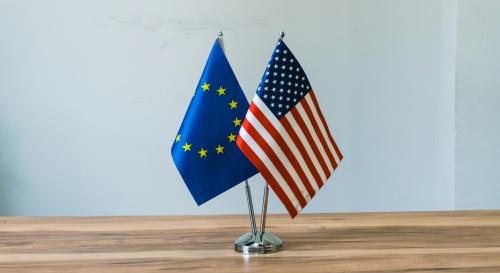 A European and US flag ontop of a wooden table 