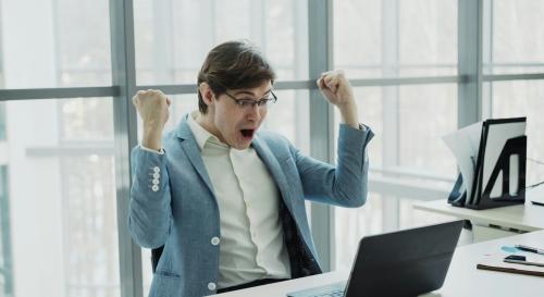 A man in a suit jacket throwing up his arms in excitement