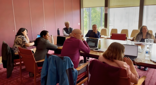 A group of scholars sat around a table having a discussion 