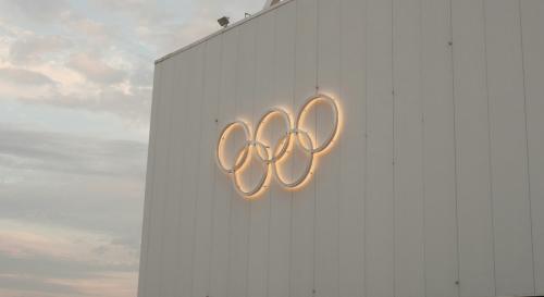 Glowing olympic rings against a white building 