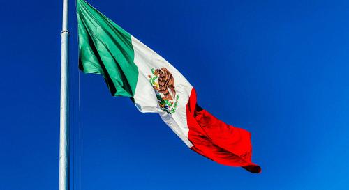 Mexican flag flying over a deep blue sky