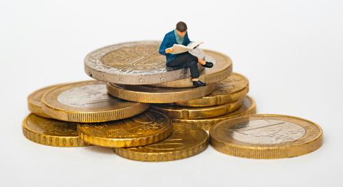 figurine man sat on top of a stack of coins