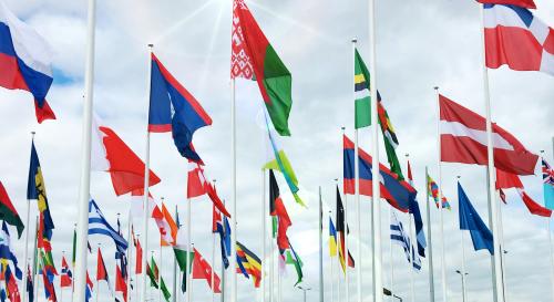 Multiple nations flags on poles in the sky