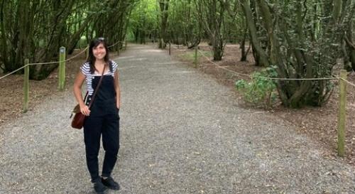 Holly Ryan stood in woodland wearing dungarees
