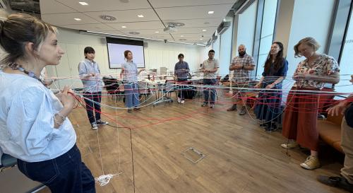 Attendees participate in interactive web-making exercise with wool in classroom