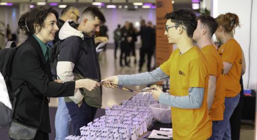 A BISA 2026 conference volunteer giving a name badge to a delegate