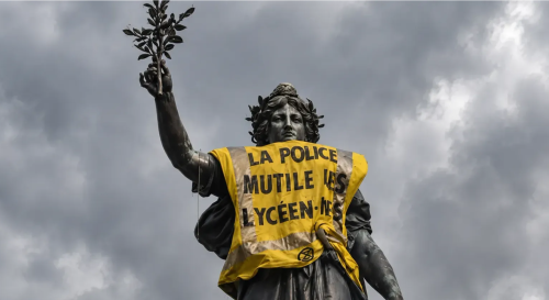 Action organised by Extinction Rebellion. Statue of Marianne at Place de la République, Paris, draped in a high-visibility yellow vest featuring the protest slogan: “La police meutile les lycéen·nes” (The police mutilate high school students)