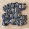 Bronze wall sculpture depicting a diverse group of overlapping human faces with varied expressions.